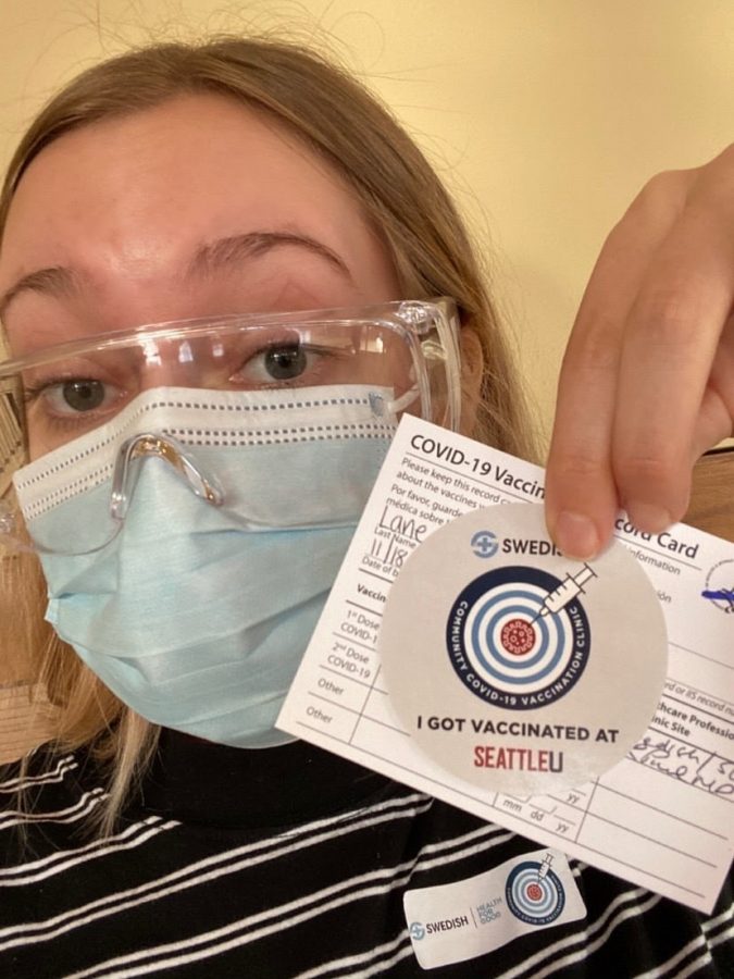 Audrey Lane poses for a selfie with her vaccine paperwork from the Seattle U vaccination site.
