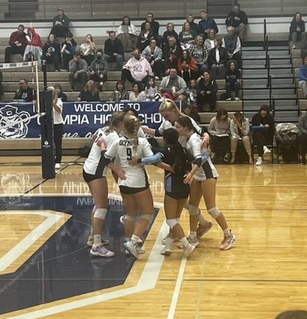 Excitement fills the air as the Olympia Bears volleyball team huddles after a score.