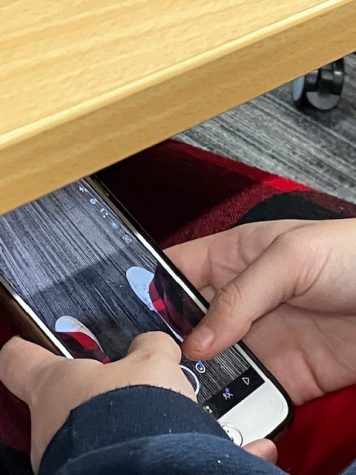 Student uses phone under table in class