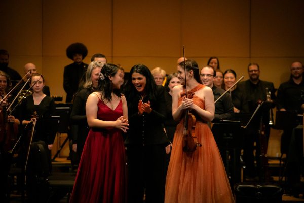 Alexandra Arrieche, Olympia Symphony Orchestra conductor congratulates Chloe Song and Ava Pakiam after their performance.