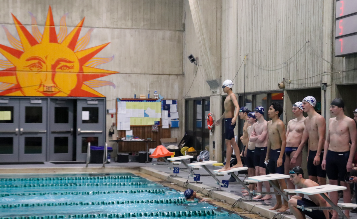 Steve+Su%2C+Kasey+Gridley%2C+and+Jack+Fuller+stand+behind+lane+five+as+Scott+Hermann+finishes+the+400+Freestyle+Relay+against+Rogers+High+School.%0A