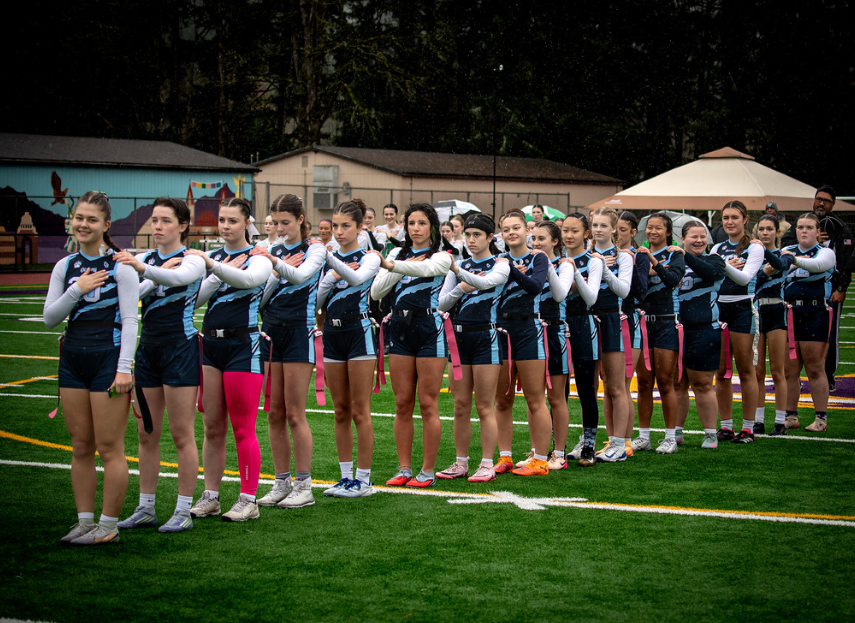 The flag football team stands for the national anthem before a league game. Flag football was recently added to help increase student involvement in athletics
