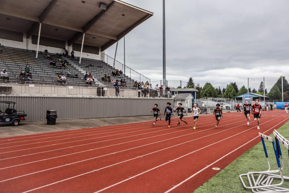Runners pushing toward the finish line in the first 100m heat.